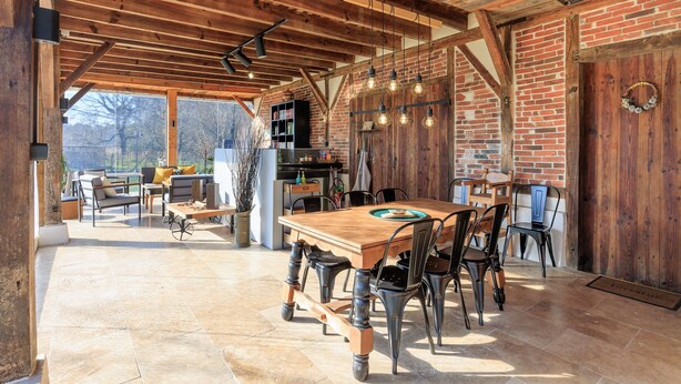 Un comedor rústico con una mesa y sillas de madera, una pared de ladrillo y vistas al exterior.