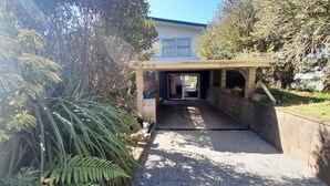 A building entrance with a gravel path leading to a covered area, surrounded by greenery and trees.