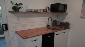 A compact kitchen with white cabinets, a wooden countertop, a black dishwasher, a microwave, and a toaster.