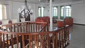 A spacious living area with a wooden staircase, a chandelier, and a red sofa.