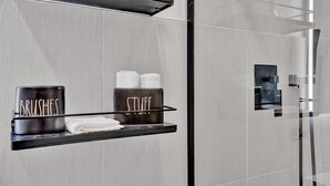 A modern bathroom with a towel rack holding two towels and a container labeled "BRUSHES" and another labeled "STUFF".