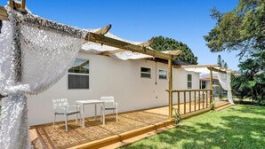 A house with a covered patio, white walls, and a wooden deck.