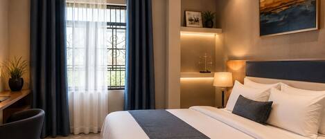 A hotel room with a bed, desk, chair, and a view of the outdoors.