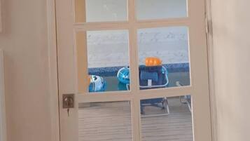 Puerta con un letrero que dice "SWIMMING POOL" y vista de muebles junto a la piscina.