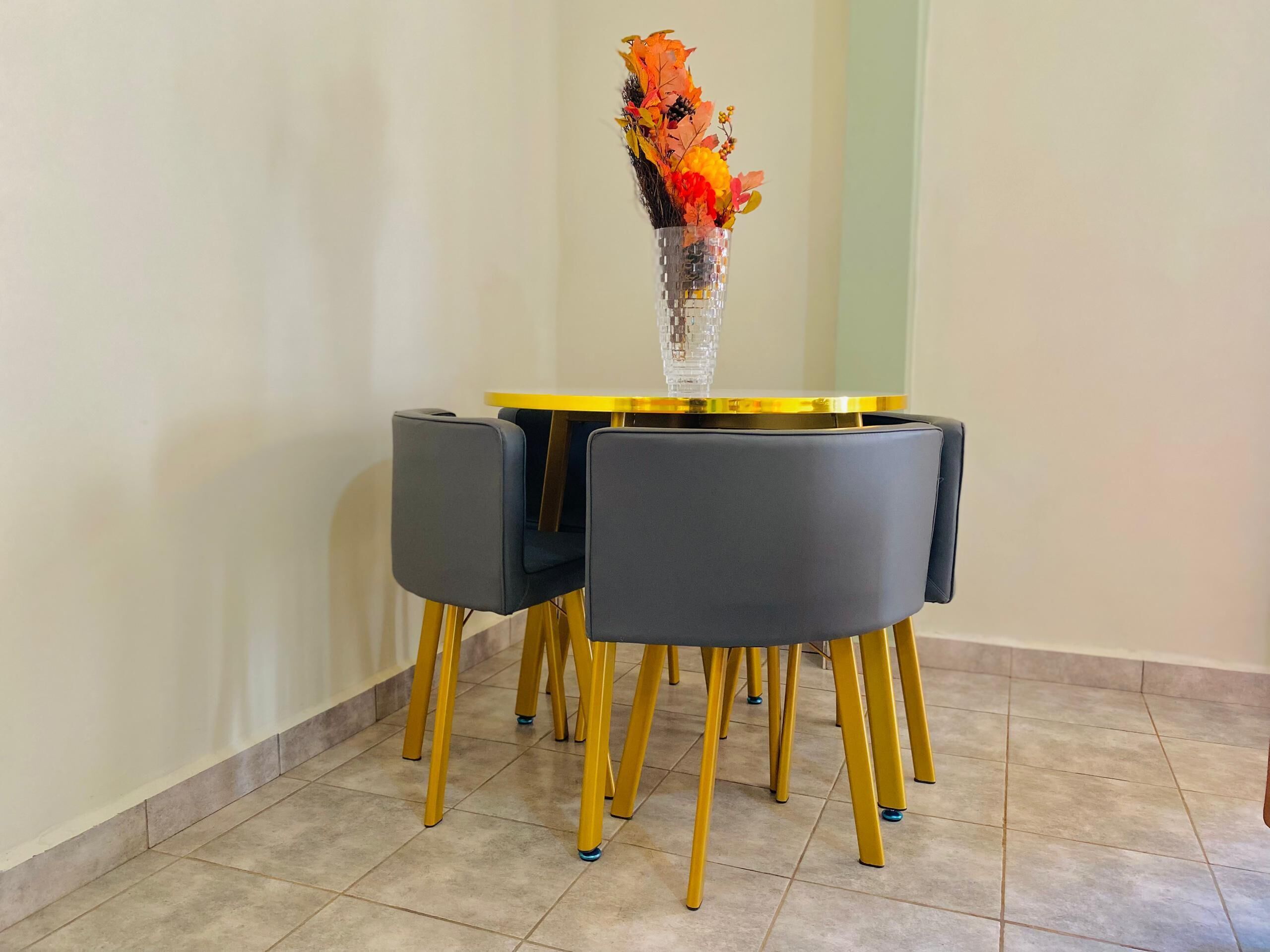 A dining table with a vase of flowers, two chairs, and a gold-colored base.