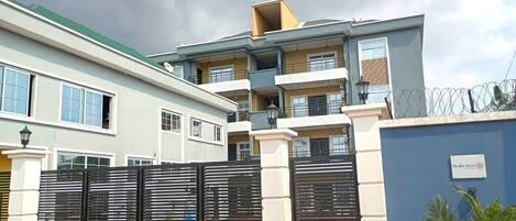 Un edificio residencial de varios pisos con entrada porticada, balcones y una pared azul con un letrero.