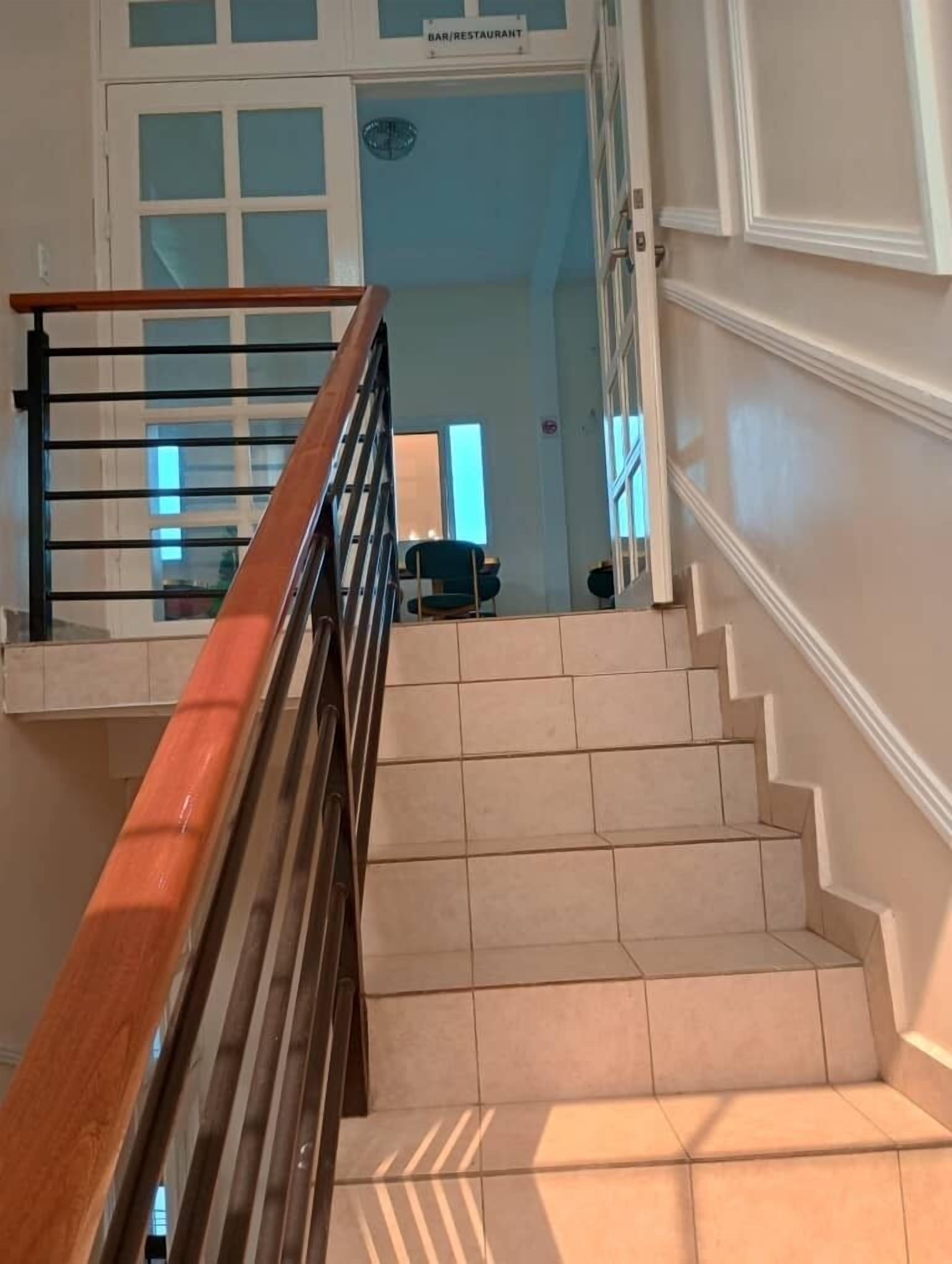 A staircase with a wooden handrail and beige tiles.