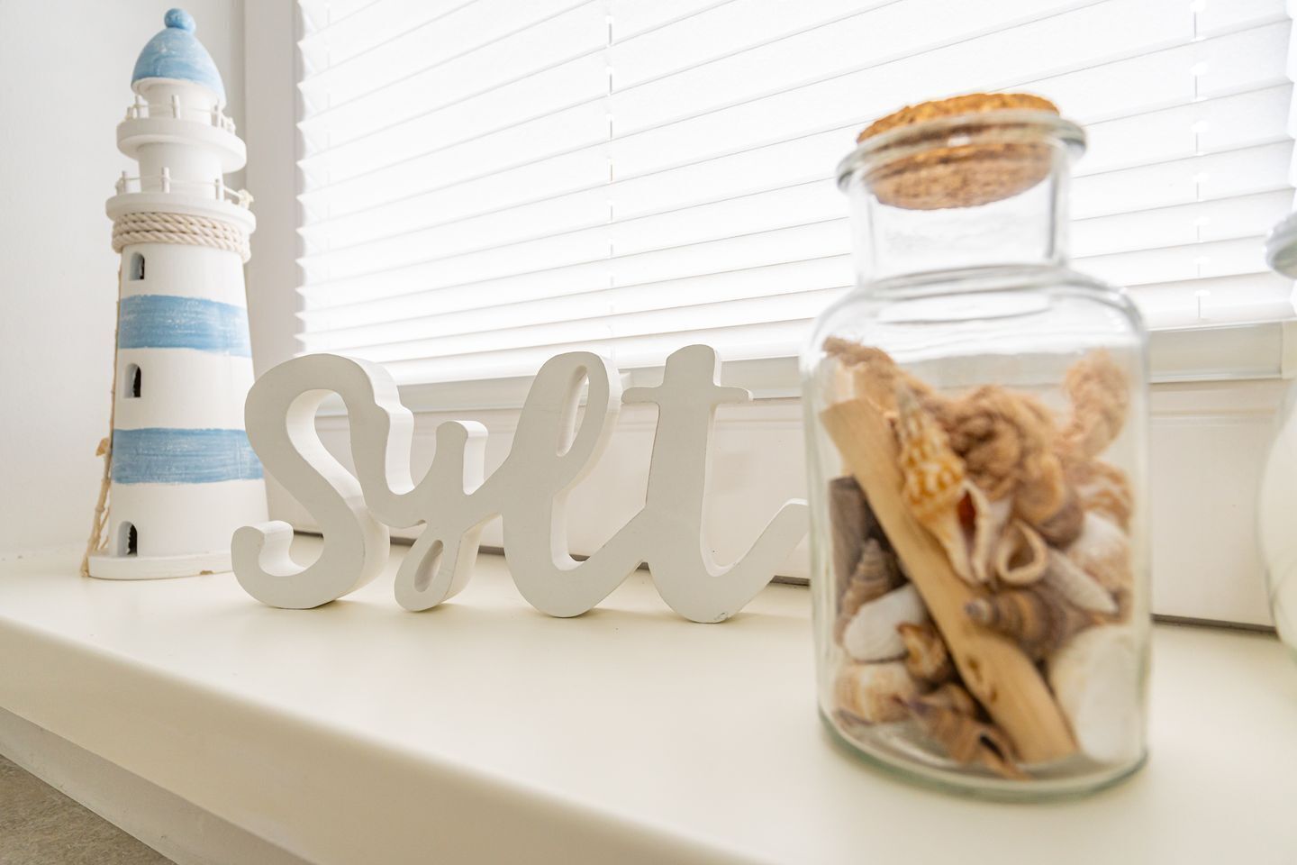 A lighthouse, a jar with sea shells, and a 'salt' sign on a window sill.