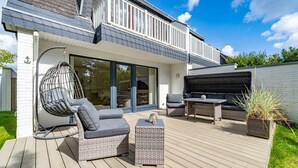 En moderne udendørs terrasse med en hængestol, en sofa og et bord.