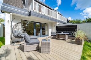 A modern outdoor patio with a hanging chair, a sofa, and a table.