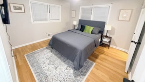 A bedroom with a bed, two bedside tables, a ceiling fan, and a window with blinds. - Cozy 3BR Retreat • Near ATL Airport & Downtown (Conley)