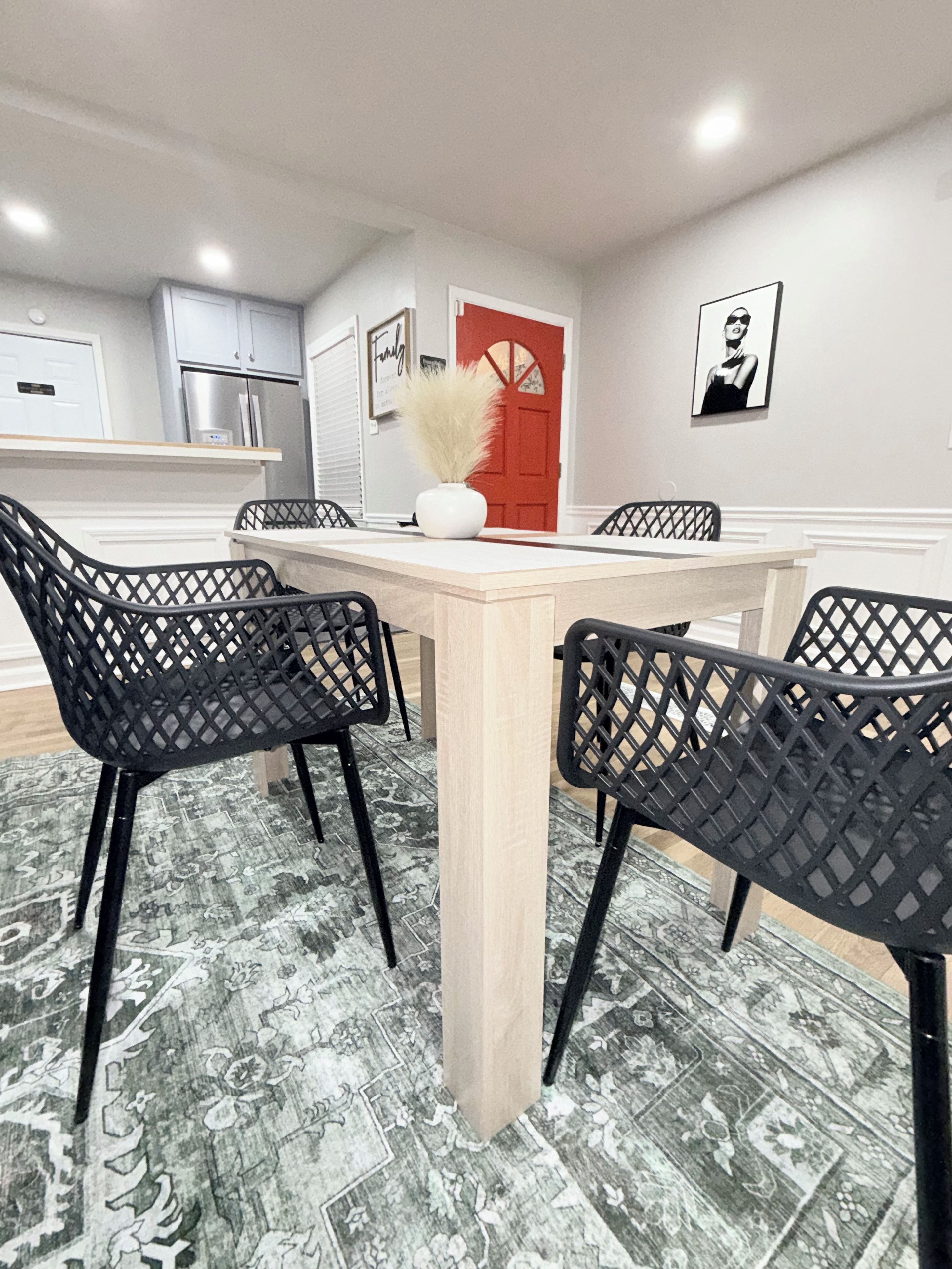 A dining area with a light-colored table and black chairs with a lattice design.