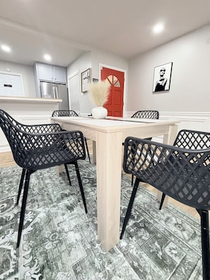 A dining area with a light-colored table and black chairs with a lattice design.