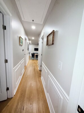 A hallway with white walls, wooden flooring, and doors leading to other rooms.