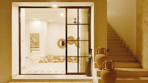Ein modernes Interieur mit einer Schiebeglastür, die zu einem Wohnbereich führt, einer Treppe und zwei Vasen auf dem Boden.