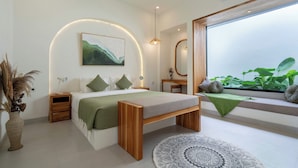 Ein modernes Schlafzimmer mit Bett, Nachttischen, einer Bank, einem großen Fenster mit Pflanzen und einer Wand-Klimaanlage.