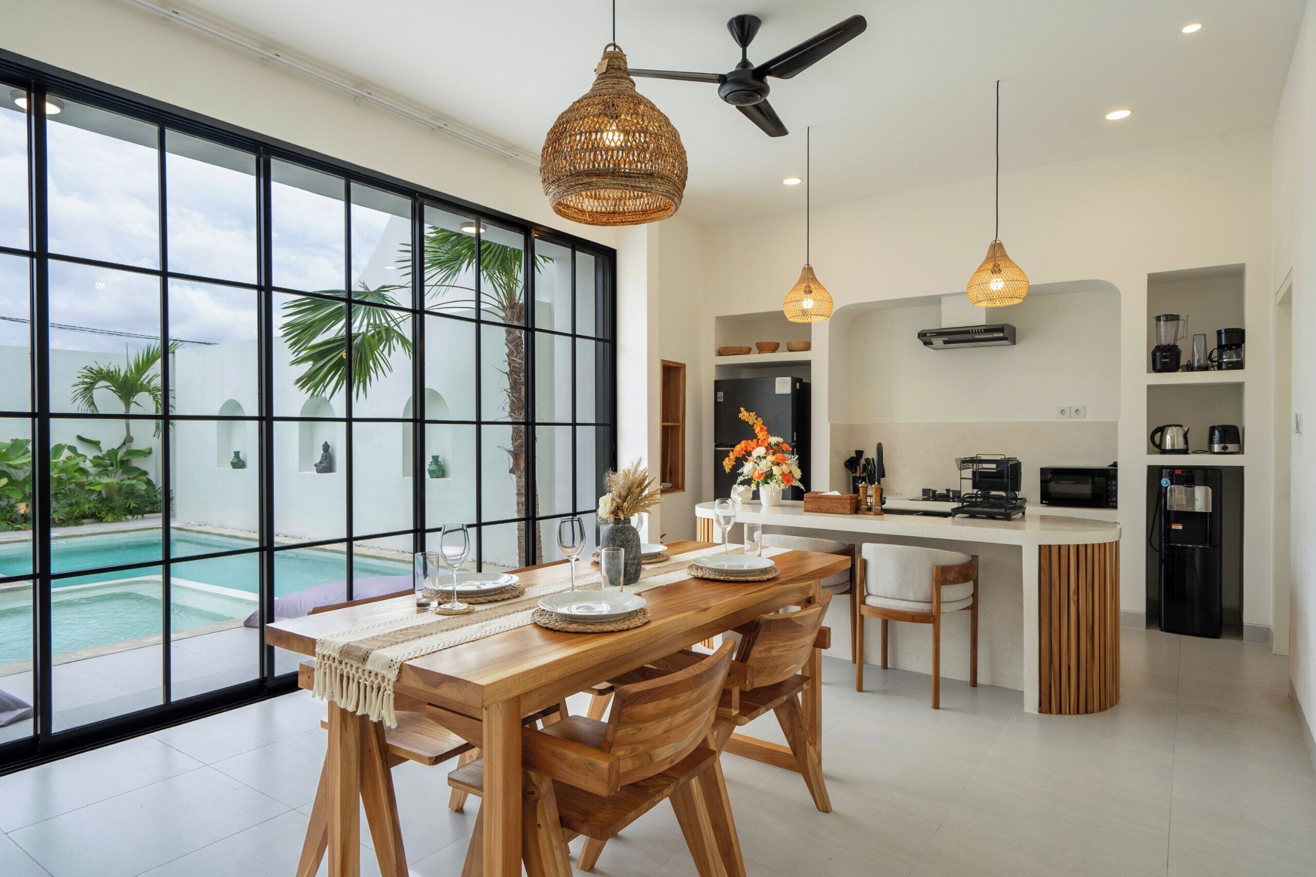 Cozinha moderna com ilha central, janelas amplas e vista para uma piscina.