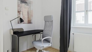 A modern office space with a desk, chair, lamp, and a window with curtains. - Nice Landstraße Studio w/ Washer & Balcony, by Blueground (Vienna)