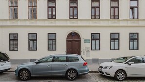 A multi-story building with a central entrance, large windows, and parked cars. - Nice Landstraße Studio w/ Washer & Balcony, by Blueground (Vienna)