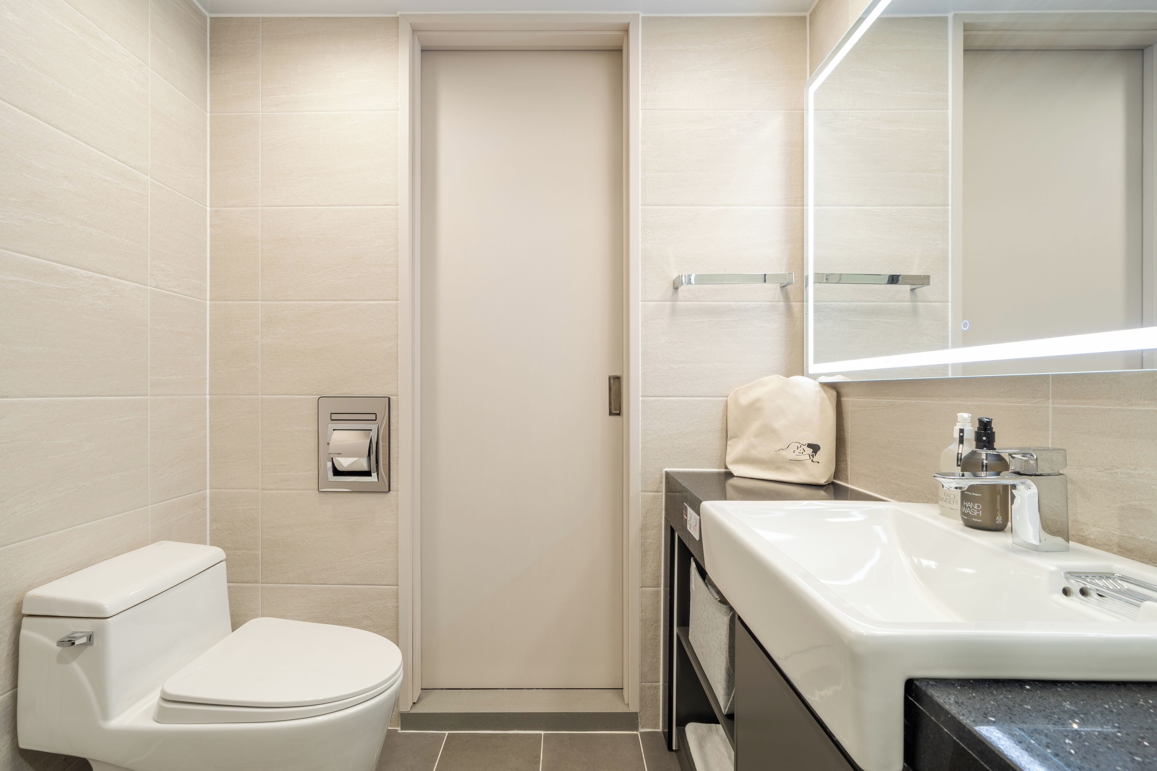 A modern bathroom with a toilet, sink, and mirror.