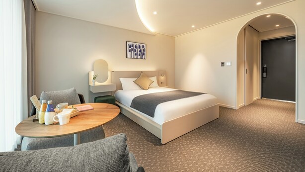 A hotel room with a bed, a round table with breakfast items, a nightstand, and a wall-mounted artwork. - Urbanstay Naksan Beach (Yangyang)