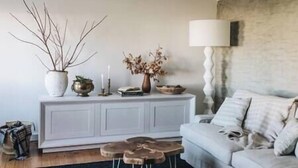Un soggiorno con un divano bianco, un tavolino con una lampada e un tavolo consolle con oggetti decorativi.