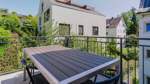 A balcony with a wooden table and chairs, surrounded by a metal railing. - Excellent Enge 3BR w/ Balcony, W/D & Elev, by Blueground (Zurich)