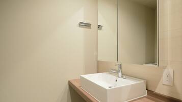 A bathroom with a white sink, a mirror, and a wooden countertop.