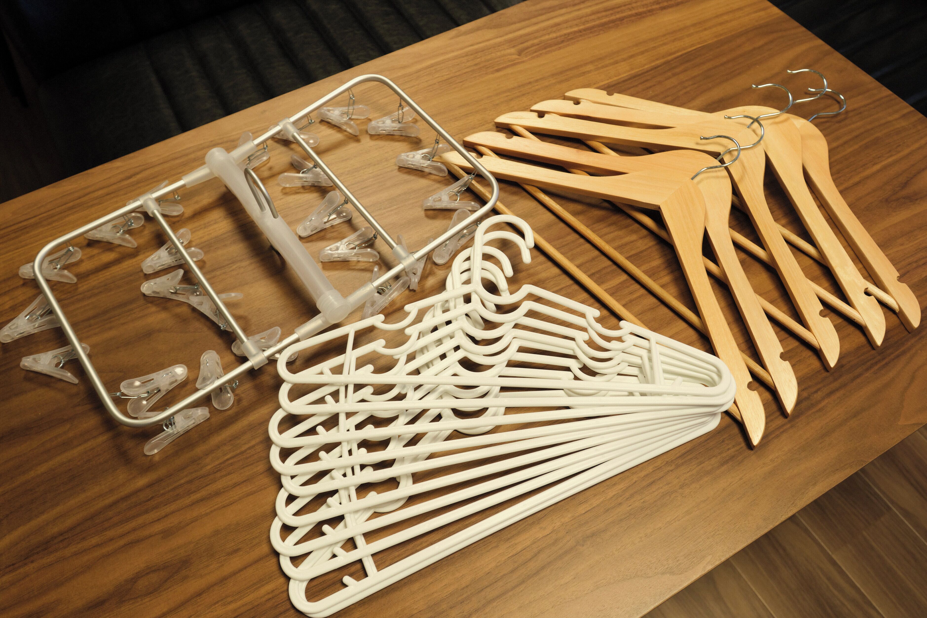 A wooden table with a metal hanger rack and wooden hangers.