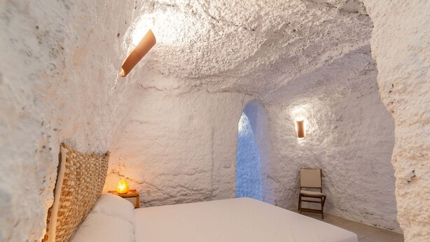 Ein gemütliches, rustikales Schlafzimmer mit einem großen Bett, einem Nachttisch mit Lampe und einem kleinen Tisch mit einer Salzlampen.
