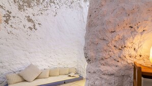 Eine gemütliche Nische mit gepolstertem Sitz, einer strukturierten Wand, einem kleinen Holztisch und einer Stehlampe.
