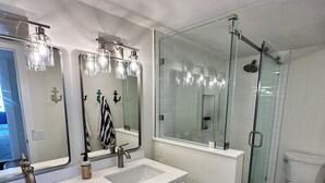 A modern bathroom with a double sink vanity, a glass shower enclosure, and a toilet. - 2 Bedroom 2 Bathroom Condo on the Beach in Park Shore (Naples)