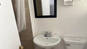 Une salle de bain avec un lavabo blanc, des toilettes et un miroir.