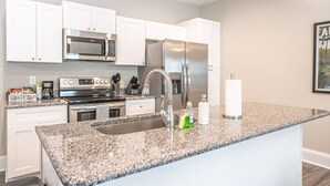 A modern kitchen with white cabinets, stainless steel appliances, and a granite countertop. - Ducks Landing Accommodations at Southern Pines Golf Course (Aberdeen)
