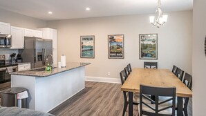 Una cocina moderna con una isla central, electrodomésticos de acero inoxidable y un comedor con mesa y sillas de madera.