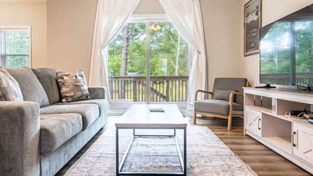 A living room with a sofa, coffee table, and TV stand. - Ducks Landing Accommodations at Southern Pines Golf Course (Aberdeen)