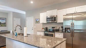 A modern kitchen with white cabinets, stainless steel appliances, and a granite countertop. - Ducks Landing Accommodations at Southern Pines Golf Course (Aberdeen)