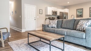 A living room with a grey sofa, a wooden coffee table, and a patterned rug. - Ducks Landing Accommodations at Southern Pines Golf Course (Aberdeen)