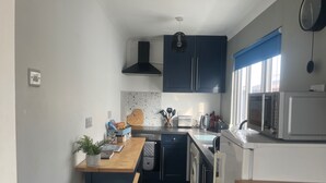 A compact kitchen with a wooden countertop, a built-in washing machine, and a microwave. - SeasideEscape-2Br-Sleeps4-Parking-PetsOK-Fireplace (Bridlington)