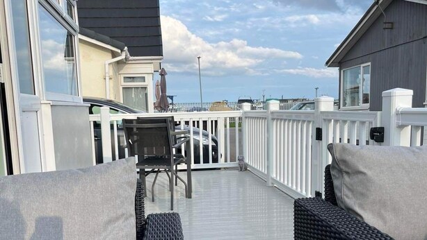 A covered outdoor seating area with wicker furniture and a view of the sea. - SeasideEscape-2Br-Sleeps4-Parking-PetsOK-Fireplace (Bridlington)