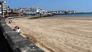 A sandy beach with a stone wall on one side and buildings in the background. - SeasideEscape-2Br-Sleeps4-Parking-PetsOK-Fireplace (Bridlington)