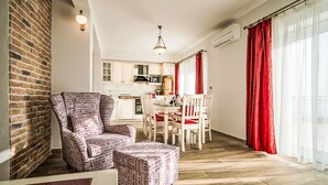 A modern living room with a brick wall, a dining area with a red and white table, and a kitchen in the background. - Bellavista by Interhome (Makarska)