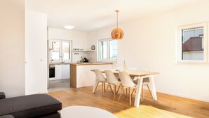 Een moderne keuken met witte kasten, een houten eettafel en een hangende hanglamp.