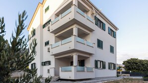 Un edificio residencial de varios pisos con balcones, techo plano y cielo despejado.