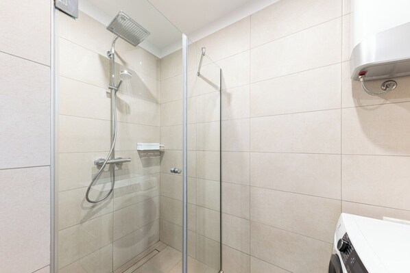 Un baño moderno con cabina de ducha de vidrio, un lavabo blanco y un perchero para toallas.