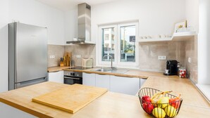 Una cocina moderna con un refrigerador de acero inoxidable, una encimera de madera, un fregadero y una ventana con vistas al exterior.
