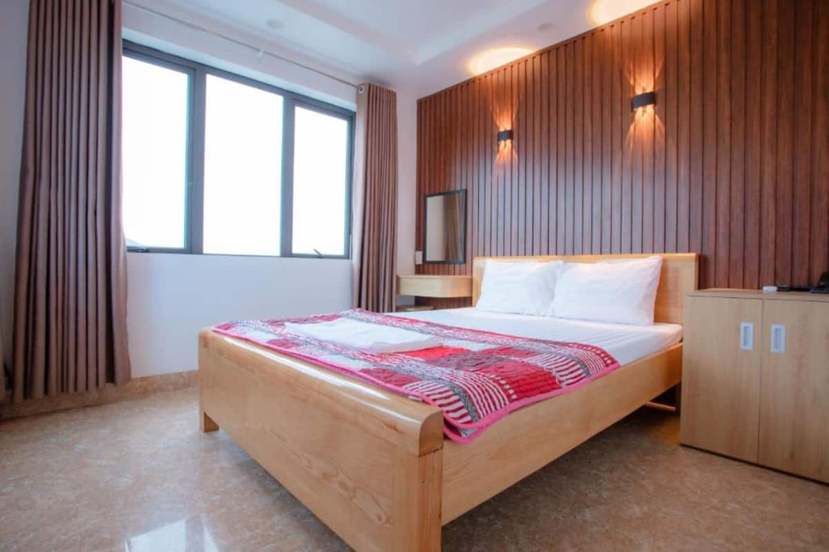 Un dormitorio moderno con una cama de madera, una mesita de noche, un armario y un ventanal con cortinas.