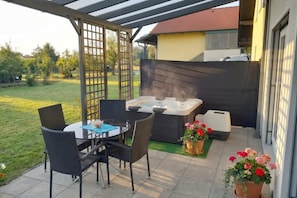 A patio with a hot tub, outdoor seating, and potted plants.