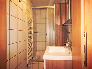 A bathroom with a white sink, wooden cabinet, and a towel rack. - Apartment Sidney by Interhome (Bad Hofgastein)