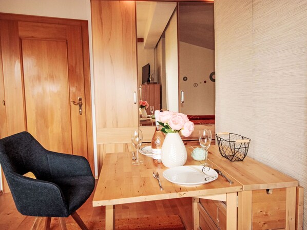 A dining table set with a vase of flowers, plates, and cutlery. - Apartment Sidney by Interhome (Bad Hofgastein)